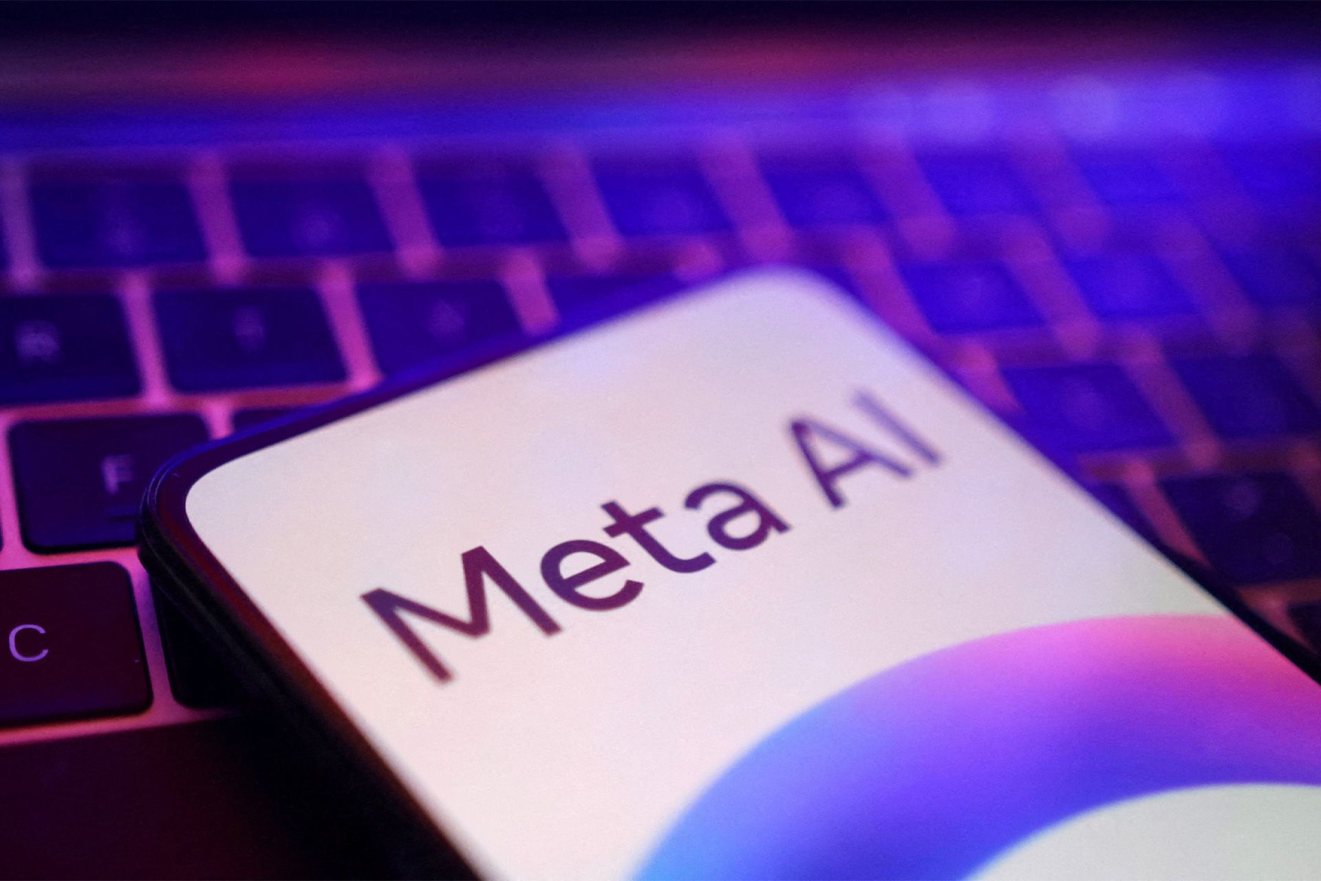 meta-ai-logo-on-phone-screen-on-laptop-66e558320232affcc50d075e-1 لوگو Meta AI روی نمایشگر گوشی قرار گرفته روی کیبورد لپتاپ از نمای نزدیک